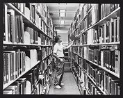 Richard (Dick) Wolfe placing a book on a shelf in Joyner Library